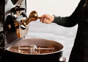 girl learning how to roast coffee beans in a coffee roaster.