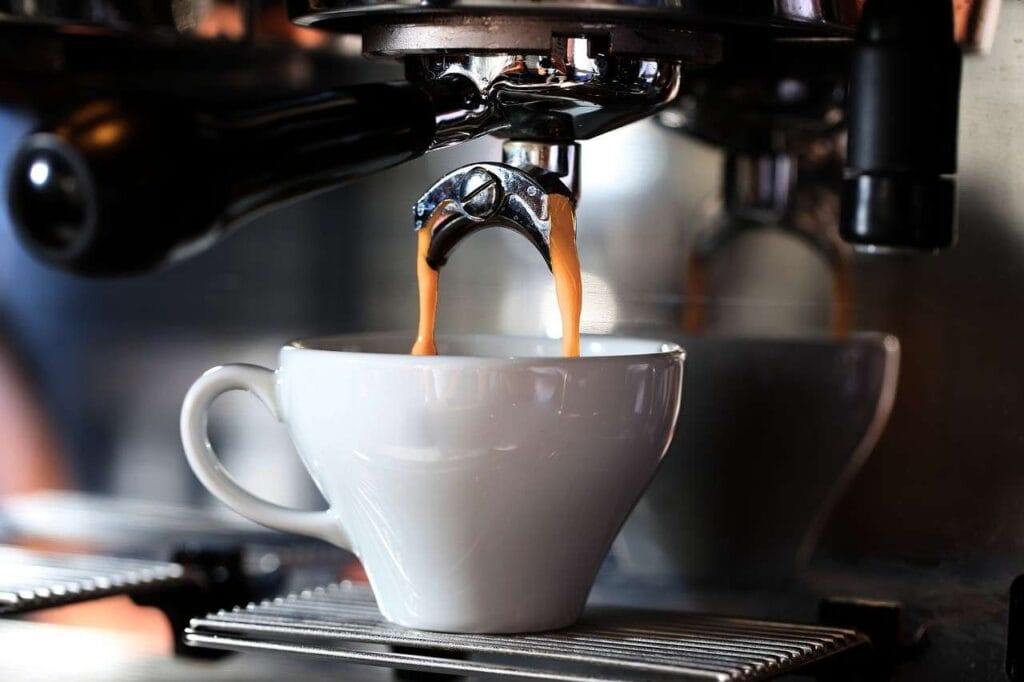 Espresso machine pouring golden coffee into a white cup