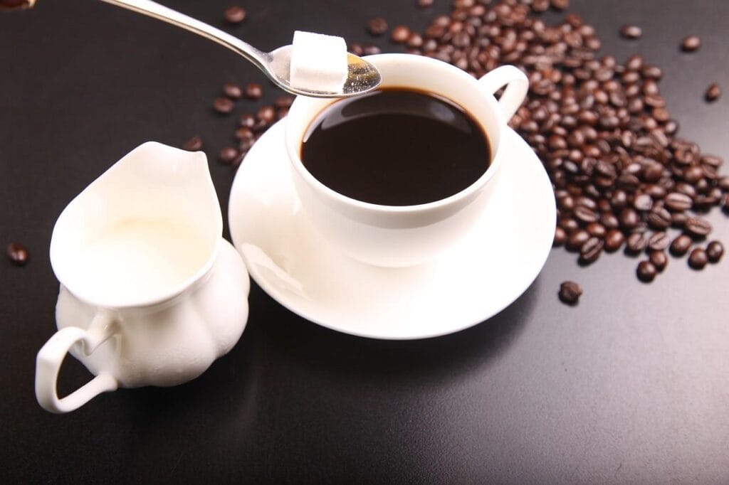 roasted coffee beans and white cup of brewed coffee