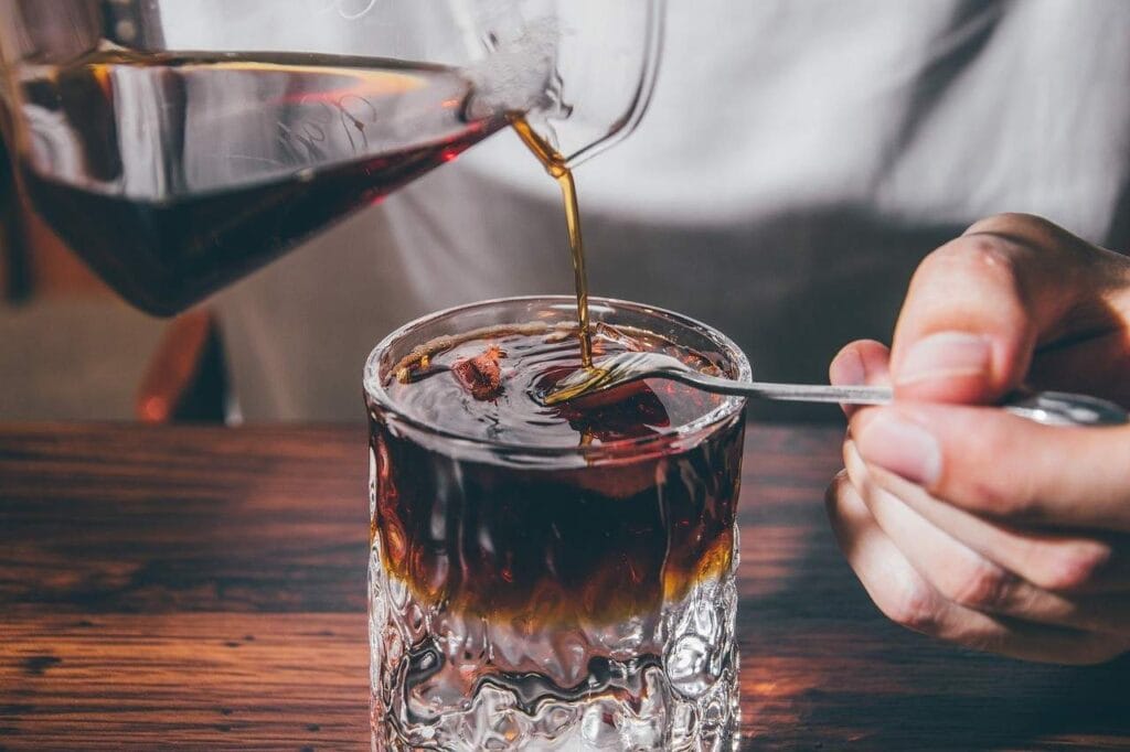 Pouring freshly brewed coffee into a glass, ready to stir and enjoy