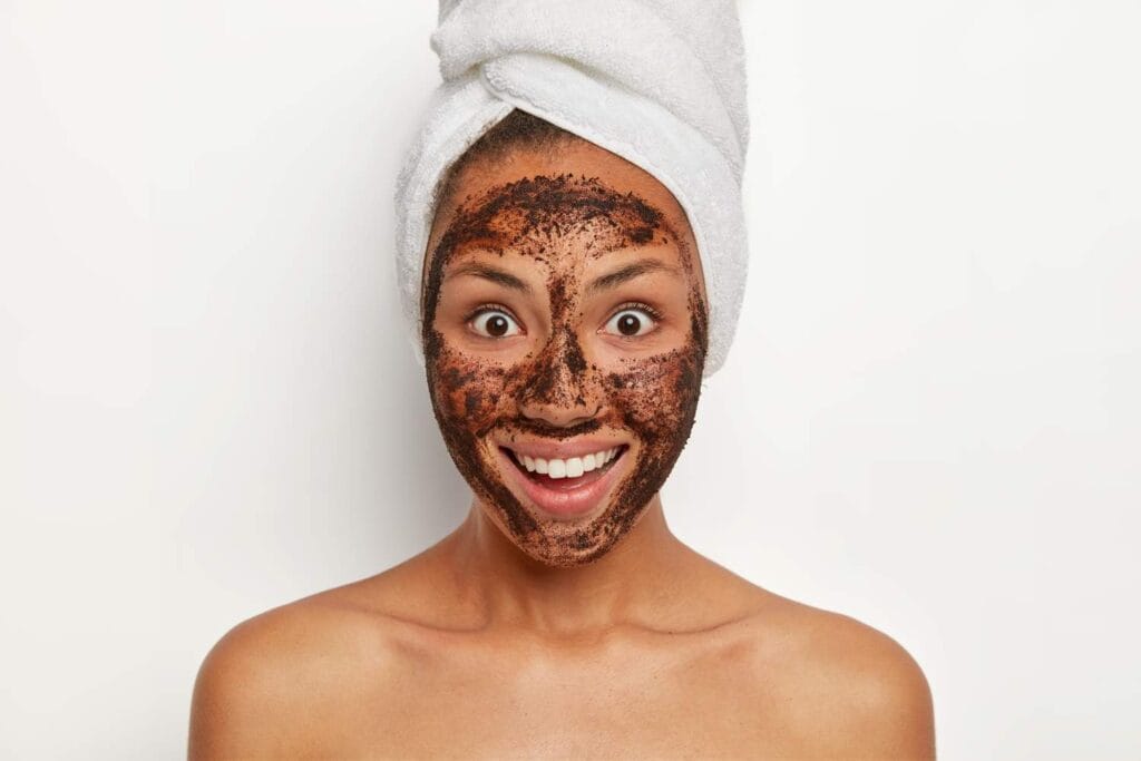 smiling girl using coffee scrub as a face mask