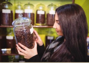 women with a coffee bean jar in hand illustrating how to check quality of coffee beans