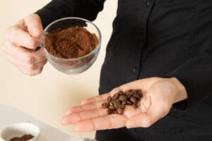 female holding roasted coffee beans and grounds illustrating can you eat ground coffee beans