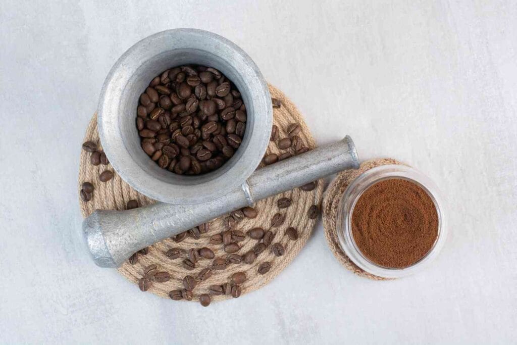 coffee beans in a mortar and pestle with cocoa in a pot